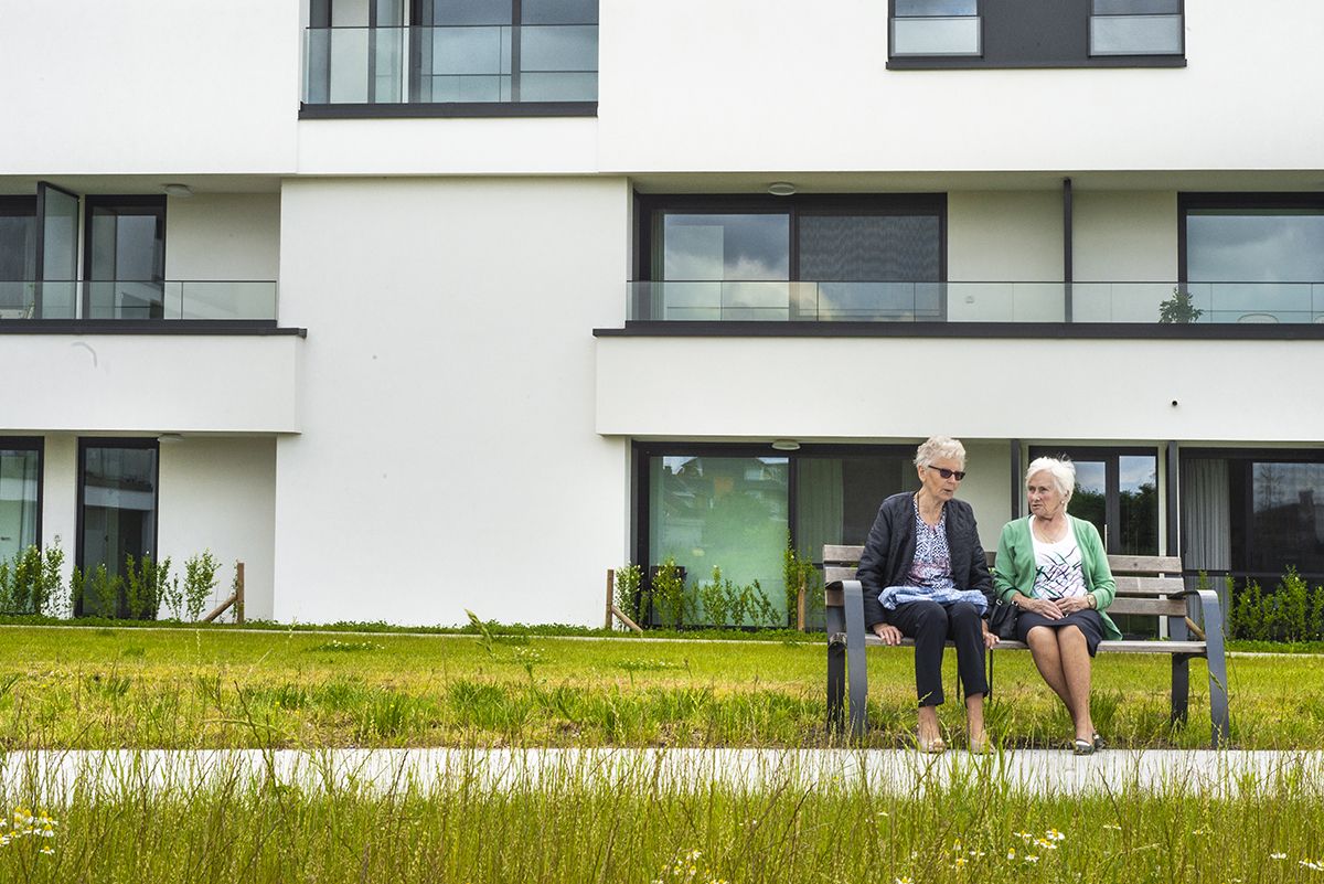 Twee bewoners op een bank in de binnentuin van Residentie Vijverhof