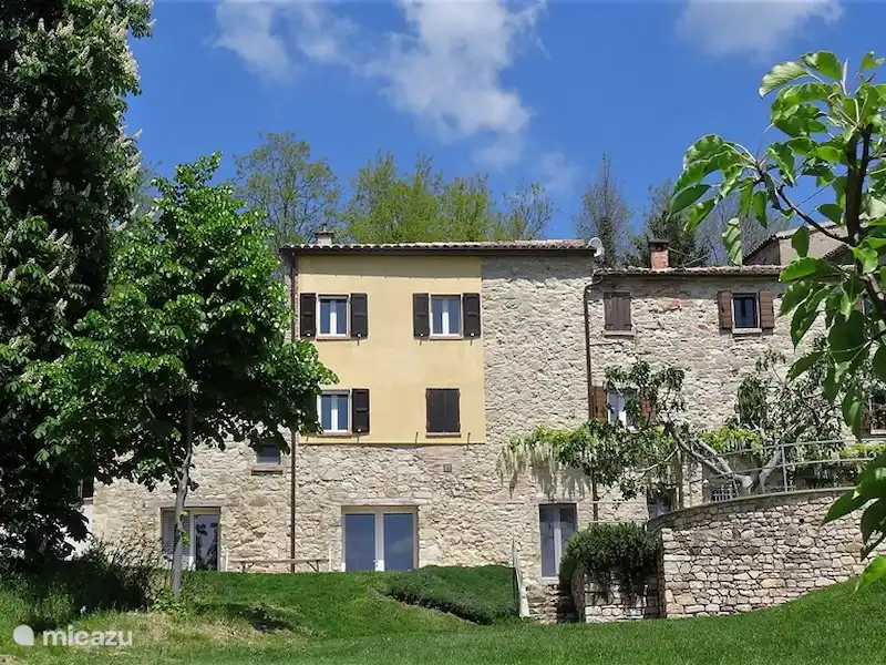 Het borgo gebouw van Casa Calénc met natuursteen en gele gevel